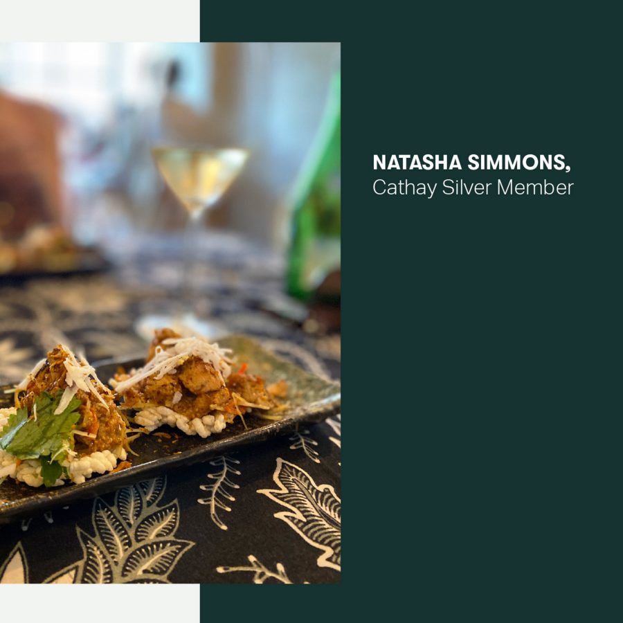 A plate of food along with two glasses of wine in the background.
